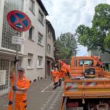 Arbeiter stellen in einer Wohnstraße provisorische Halteverbotsschilder auf.
