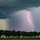 Ein Blitz leuchtet über der Landschaft. Gewitter und Starkregen sorgen in NRW für Abkühlung.