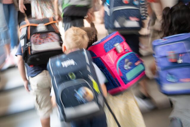 Schüler mit bunten Schulranzen stürmen eine Treppe hoch.