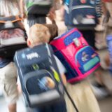 Schüler mit bunten Schulranzen stürmen eine Treppe hoch.