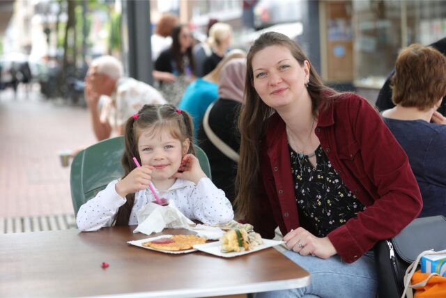 Frau und Kind essen Waffel und Kuchen