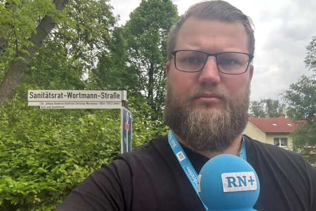 Ein Reporter aus Lünen steht vor dem Schild der Sanitätsrat-Wortmann-Straße.