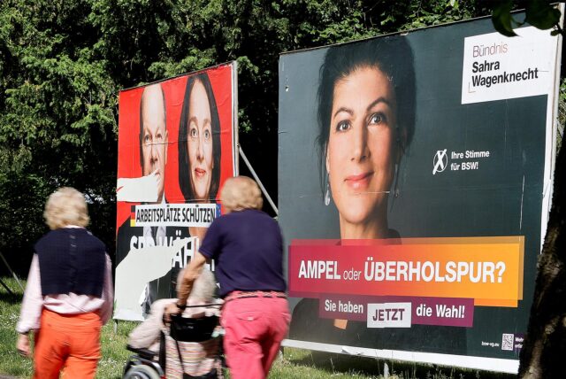 Ein Gruppe von Passanten geht an großen Wahlplakaten vorbei, auf denen auch BSW-Gründerin und Namensgeberin Sahra Wagenknecht zu sehen ist.