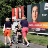 Ein Gruppe von Passanten geht an großen Wahlplakaten vorbei, auf denen auch BSW-Gründerin und Namensgeberin Sahra Wagenknecht zu sehen ist.