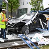 Ein Polizist steht neben dem Unfallfahrzeug in den Glassplittern einer Haltestelle.