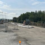 Baustelle an der L821n in Bergkamen. Der Bereich ist mit Bauzäunen abgesperrt und es stehen ein Bagger und ein Kran dort.