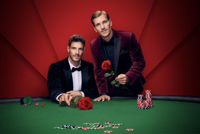 Martin Braun (links) und Felix Stein (rechts) – die beiden Single-Männer in der neuen Staffel „Die Bachelors“ – hinter einem Poker-Tisch mit Poker-Chips und Rosen