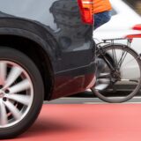 Ein Fahrrad fährt neben einem Auto her.