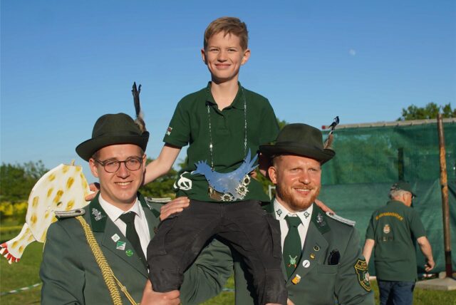 Jona Borgmann wird als neuer Kinderschützenkönig des Schützenvereins Bentrop von zwei Schützen auf Schultern getragen.