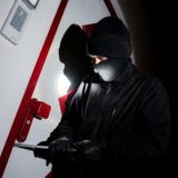 Ein Mann versucht mithilfe einer Brechstange eine Tür aufzuhebeln.
