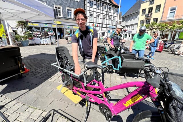 Auf dem Bild ist ein Mann zu sehen, der neben einem E-Lastenrad steht.