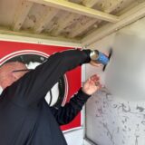 Mann überdeckt Schmierereien mit Farbe aus einer Sprühdose.