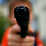 Ein Mann zielt mit einer Pistole in Richtung Kamera (Symbolfoto für einen bewaffneten Bankraub).