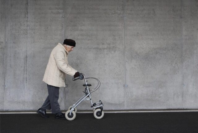 Eine ältere Dame geht an einem Rollator.