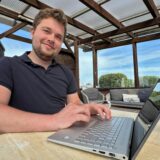 Ein Mann sitzt an einem Tisch vor seinem Laptop.