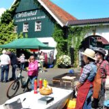 Ausflügler bummeln an einem Bratwurststand vor dem Gutshof Wellenbad an der Ruhr in Schwerte vorbei.