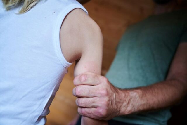 Ein Mann hält ein Kind am Arm.