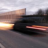 Ein Fahrzeug fährt in der Morgendämmerung auf die Brücke der Heringerstraße über die A44 und hinterlässt dabei auf der Kamera eine Lichtspur.