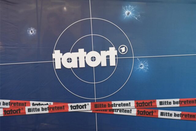 Auf einer Fotorückwand sind das Logo der Fernsehreihe «Tatort», Einschusslöcher und Absperrband abgebildet.