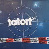 Auf einer Fotorückwand sind das Logo der Fernsehreihe «Tatort», Einschusslöcher und Absperrband abgebildet.
