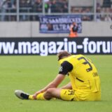 Yannik Lührs sitzt auf dem Rasen und steckt seinen Kopf in sein Trikot.