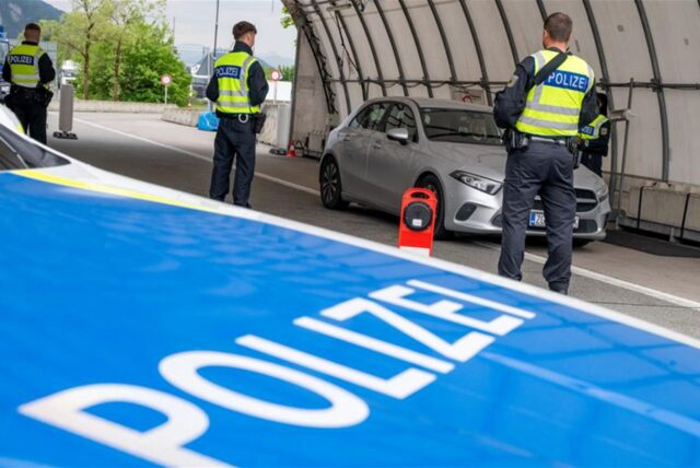 Polizisten kontrollieren an der Grenze ein Auto.