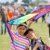 Zwei Mädchen stehen mit einem Drachen auf dem Gelände des Drachenfestivals Kamen Kite