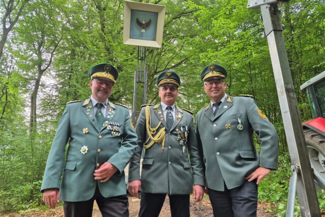 Drei Schützen stehen vor dem Vogel am Schützenschießstand beim Westhofener Schützenfest.