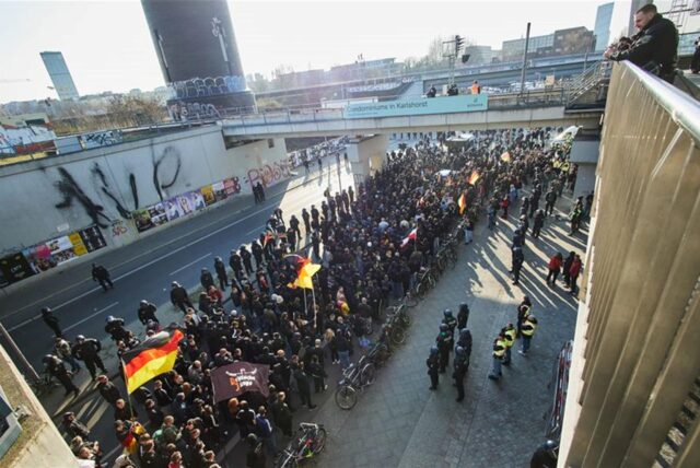 Teilnehmer einer rechtsextremistischen Demonstration werden von der Polizei unter die Gleisbrücken geführt.