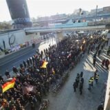 Teilnehmer einer rechtsextremistischen Demonstration werden von der Polizei unter die Gleisbrücken geführt.