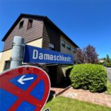 Ein Polizist mit Handschellen und einer Pistole am Gürtel steht vor einem Streifenwagen.