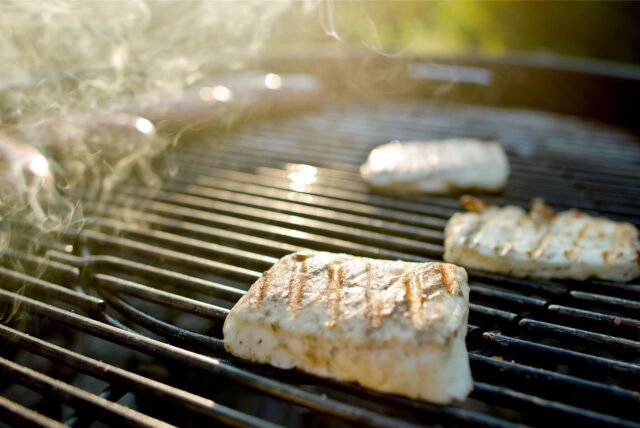 Drei Stücke Halloumi-Grillkäse liegen auf einem Kugelgrill.