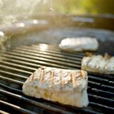 Drei Stücke Halloumi-Grillkäse liegen auf einem Kugelgrill.