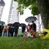Blumen liegen in der Nähe einer Unglücksstelle einer Hochbrücken-Baustelle an einem Baum.