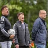 Lorenz Wagener (M.) steht neben zwei Männern und ärgert sich.