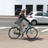 Eine junge Frau fährt mit ihrem Fahrrad vom freigegebenen Gehweg aus auf den Ostring zu. Dort muss sie sich in den fließenden Autoverkehr einordnen.