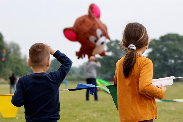 Zwei Kinder betrachten bei der GSW Kamen Kite einen großen Drachen in Form einer braunen Maus.