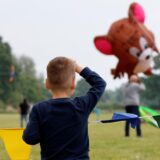 Zwei Kinder betrachten bei der GSW Kamen Kite einen großen Drachen in Form einer braunen Maus.