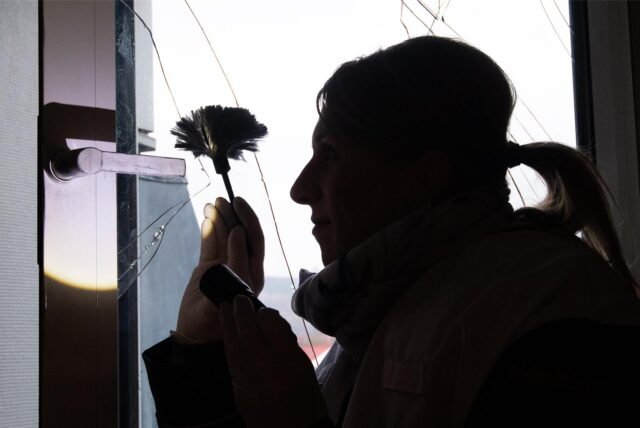 Eine Polizistin sammelt Fingerabdrücke an einem zerbrochenen Fenster.