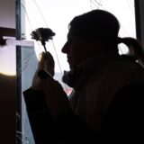 Eine Polizistin sammelt Fingerabdrücke an einem zerbrochenen Fenster.