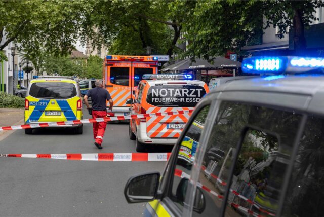 Rettungskräfte und Polizei stehen in Essen hinter Absperrungen mit Flatterband.