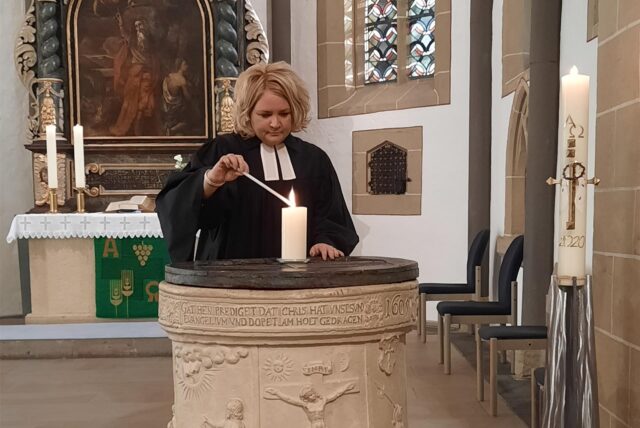 Sandra Sternke-Menne steht in der Ev. Kirche in Dortmund-Brackel und zündet eine Kerze an.