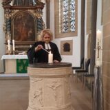 Sandra Sternke-Menne steht in der Ev. Kirche in Dortmund-Brackel und zündet eine Kerze an.