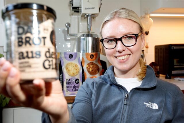 Müllermeisterin Lisa Sendker aus Kamen hält lächelnd ein Glas mit der Aufschrift „Das Brot aus dem Glas“ in die Kamera.