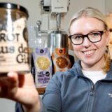 Müllermeisterin Lisa Sendker aus Kamen hält lächelnd ein Glas mit der Aufschrift „Das Brot aus dem Glas“ in die Kamera.