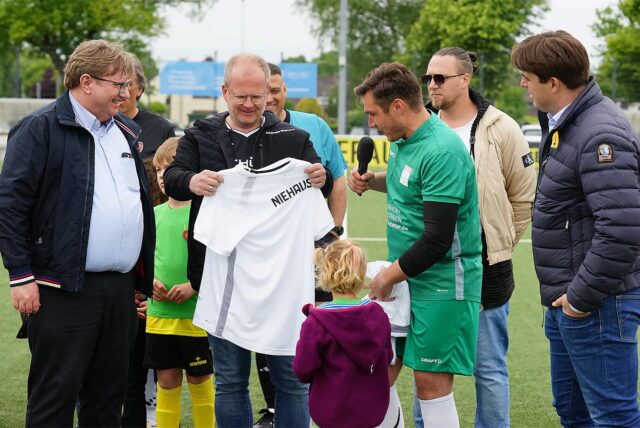 Ein Fußballspieler hält ein weißes Trikot in der Hand.