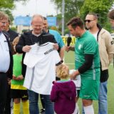 Ein Fußballspieler hält ein weißes Trikot in der Hand.