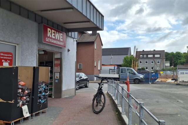 Der Getränkemarkt von Rewe an der Lünener Straße. Davor steht ein Fahrrad, auf dem Parkplatz steht ein Jaguar, dahinter ein Kleinlastwagen.