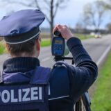 Eine Polizistin misst mit einem Lasergerät die Geschwindigkeit von vorbeifahrenden Autos. Auf dem Display des Geräts sind 74 km/h zu erkennen.