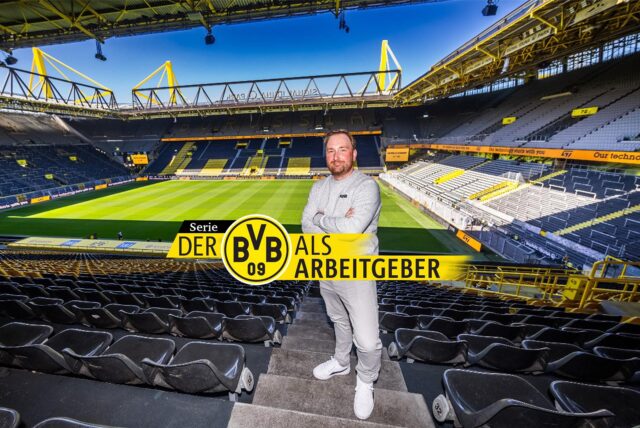 Chmielewski steht zwischen den Zuschauerrängen im Stadion, im Hintergrund sieht man das Spielfeld